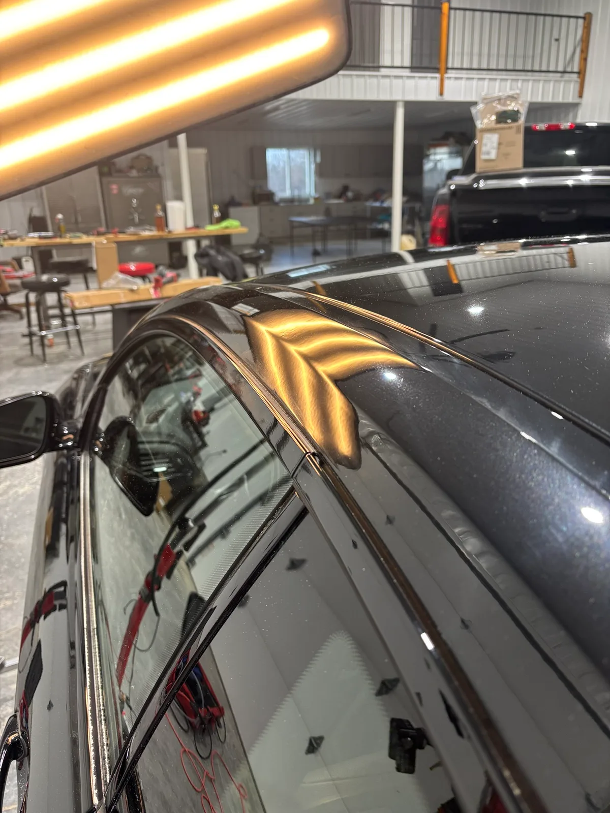 Paintless dent repair rod in action behind a vehicle panel, performing a repair pass