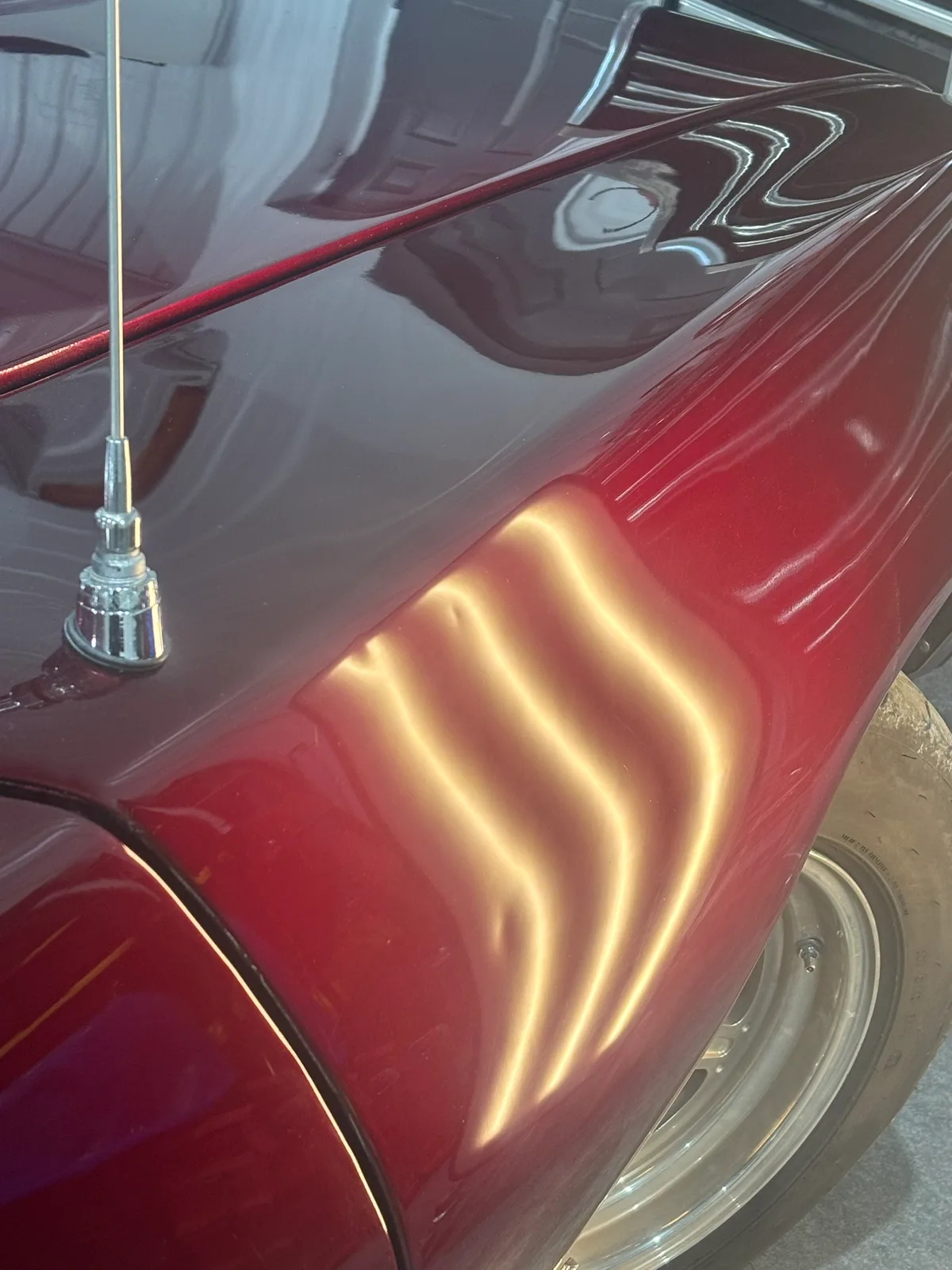 Multiple hail dents revealed by LED line-board light on a Pontiac GTO quarter panel at the Hail Solutions Olathe shop