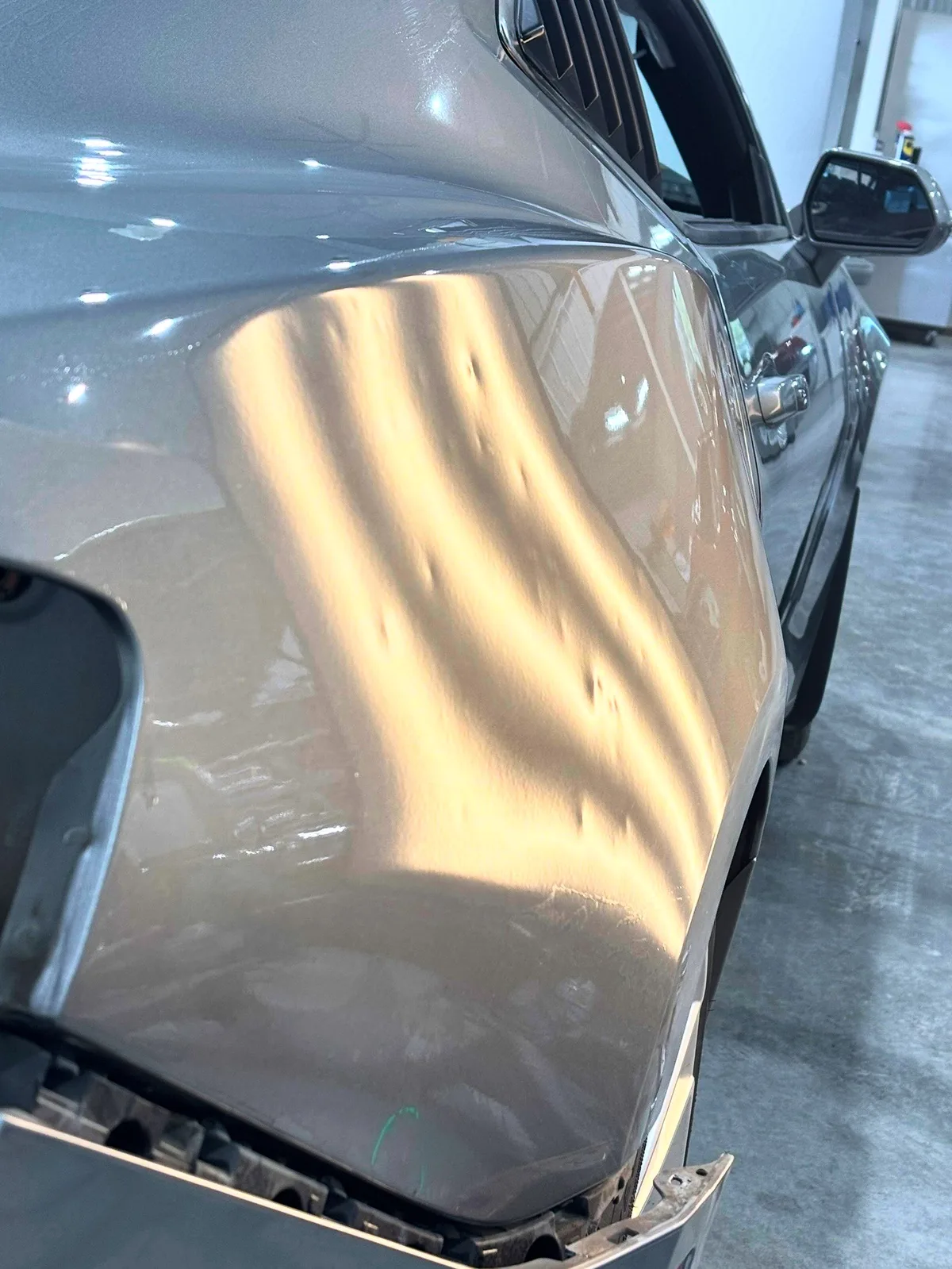 Camaro fender with bumper removed under LED line-board inspection at Hail Solutions — aluminum hail damage repair assessment