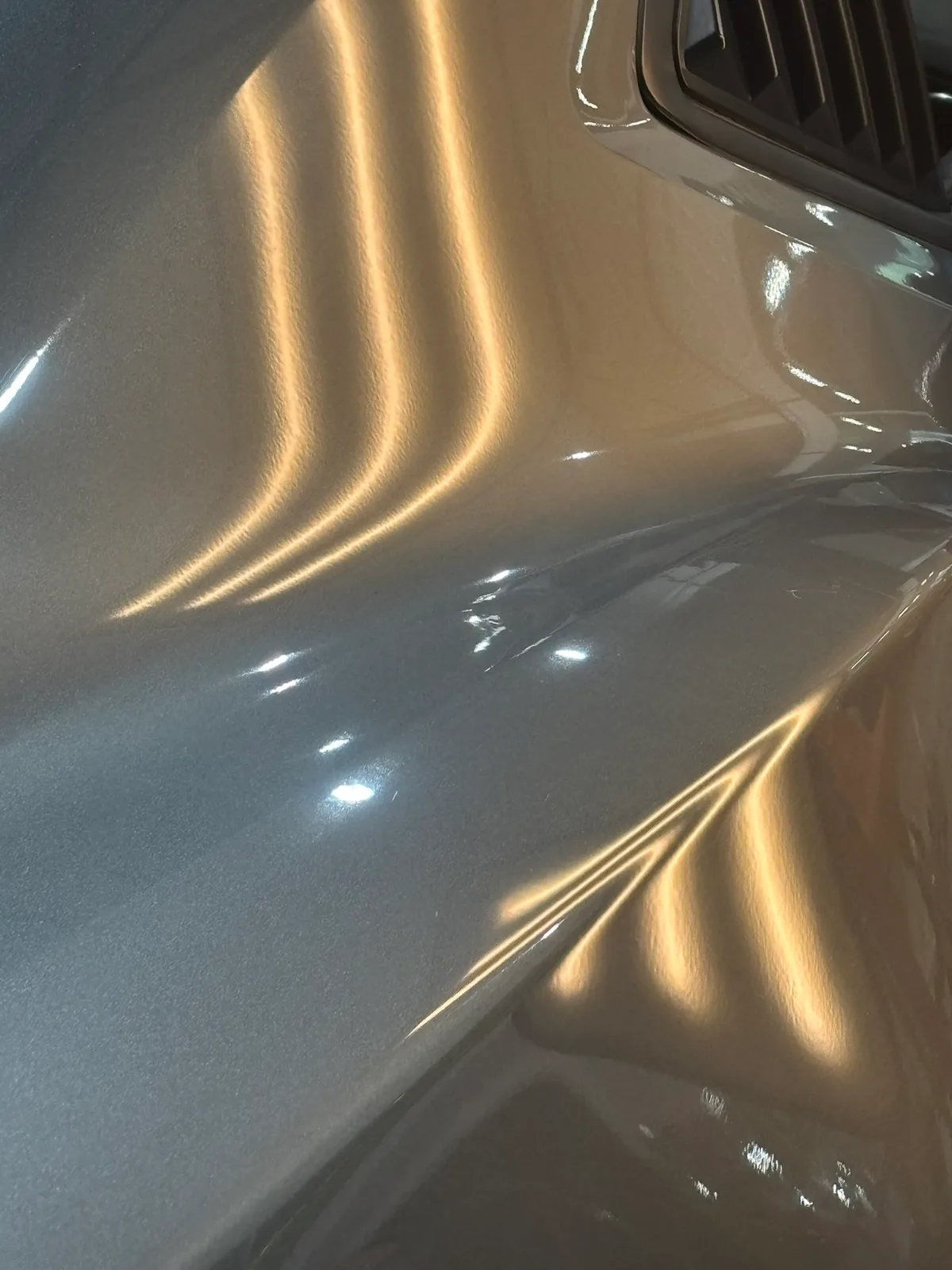 Severe hail damage distortion on a vehicle quarter panel revealed by LED line-board at the Hail Solutions shop
