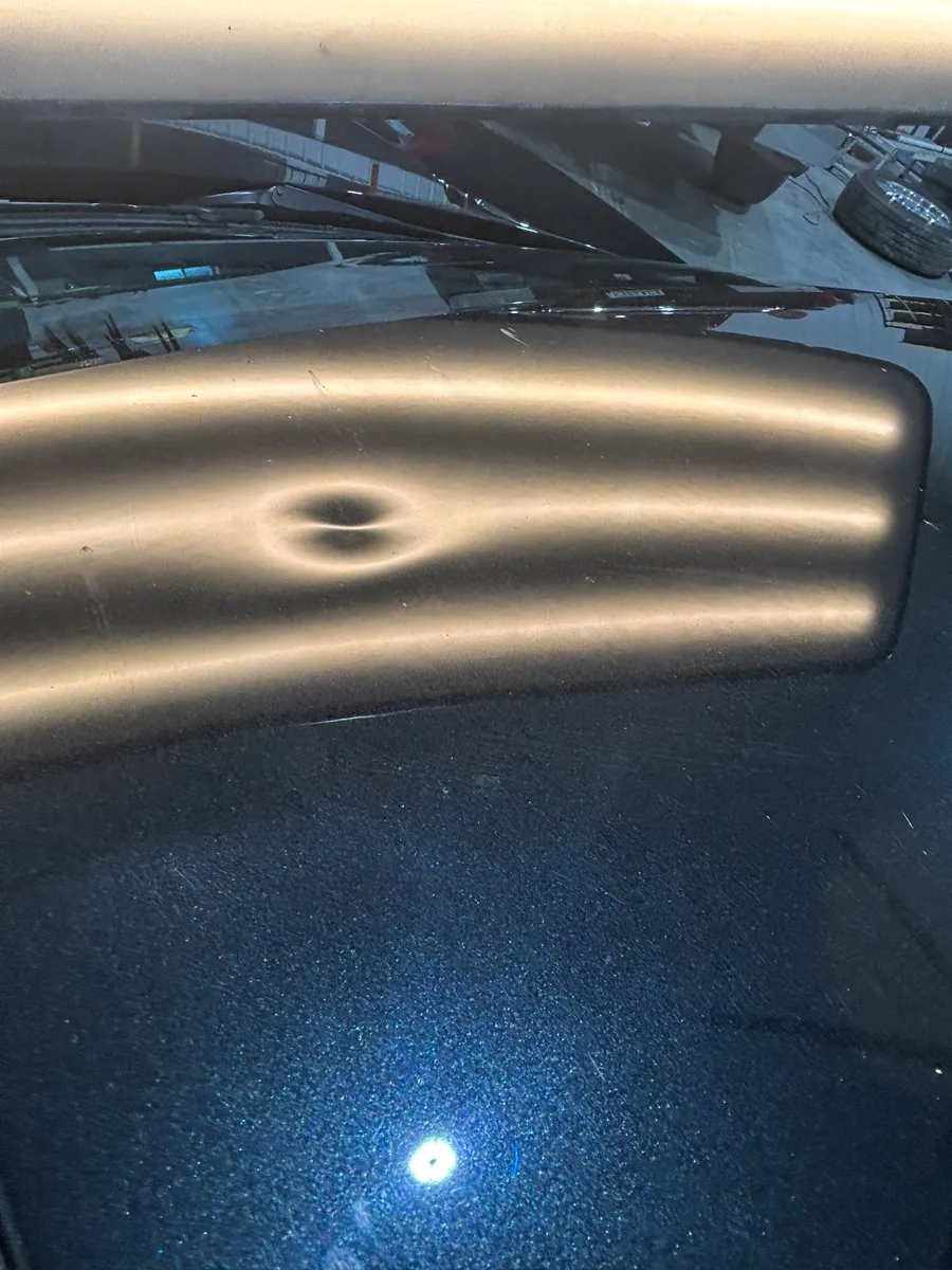 Severe hail damage on a vehicle hood revealing the typical dent pattern