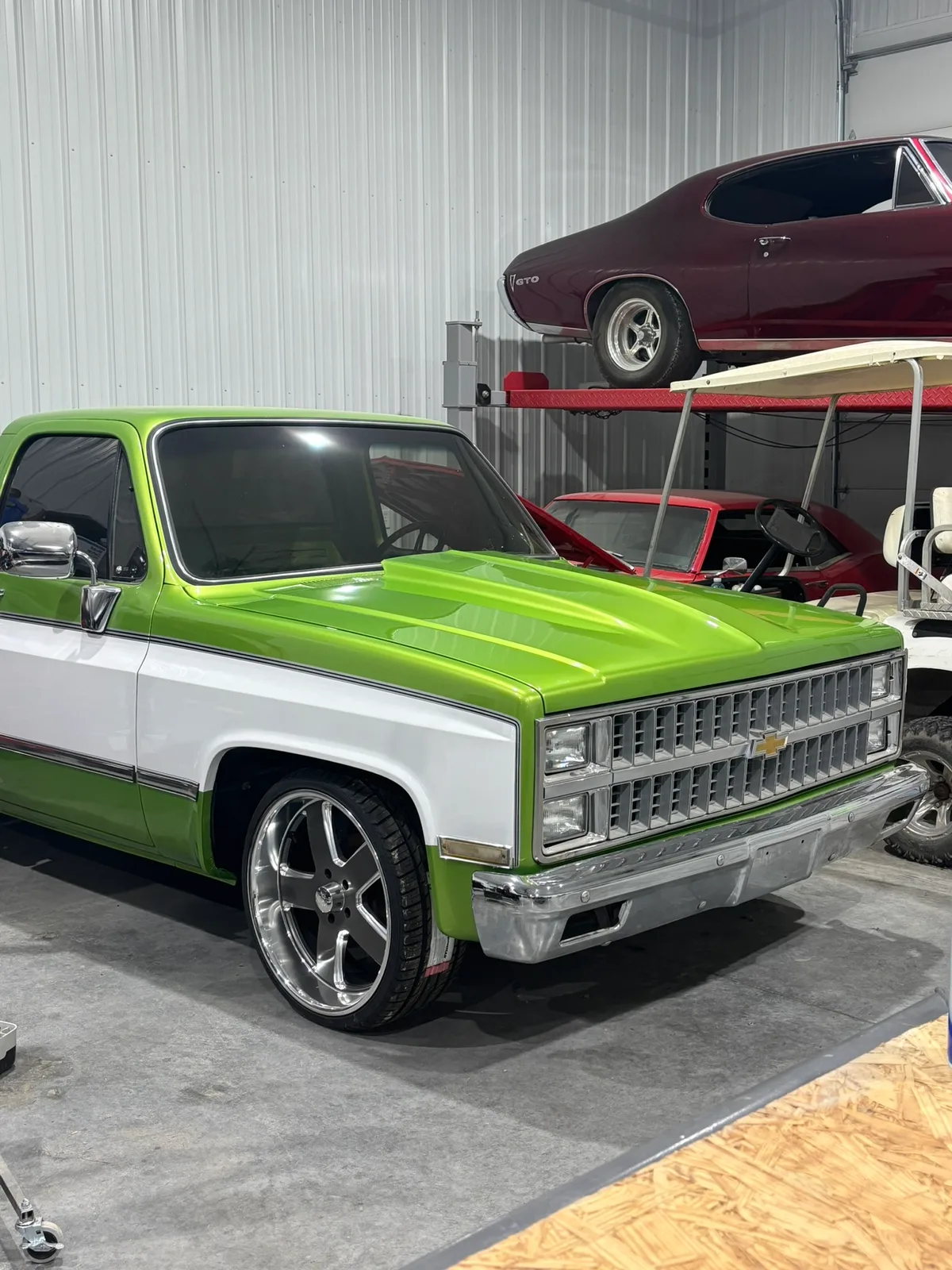 Restored green and white classic Chevrolet C10 truck in the Hail Solutions shop bay after paintless dent repair in Olathe Kansas