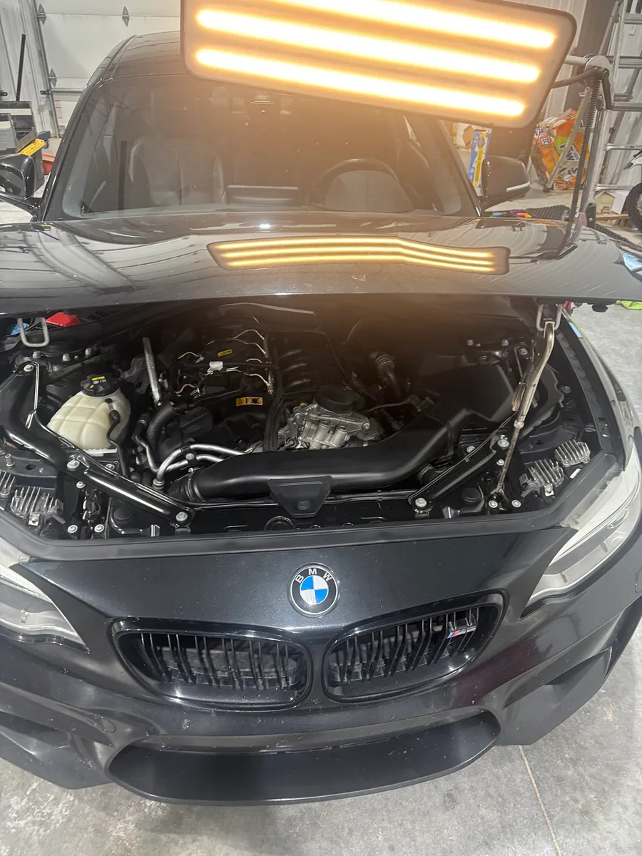 BMW in the Hail Solutions shop bay with the engine bay lit by an LED line-board for damage assessment